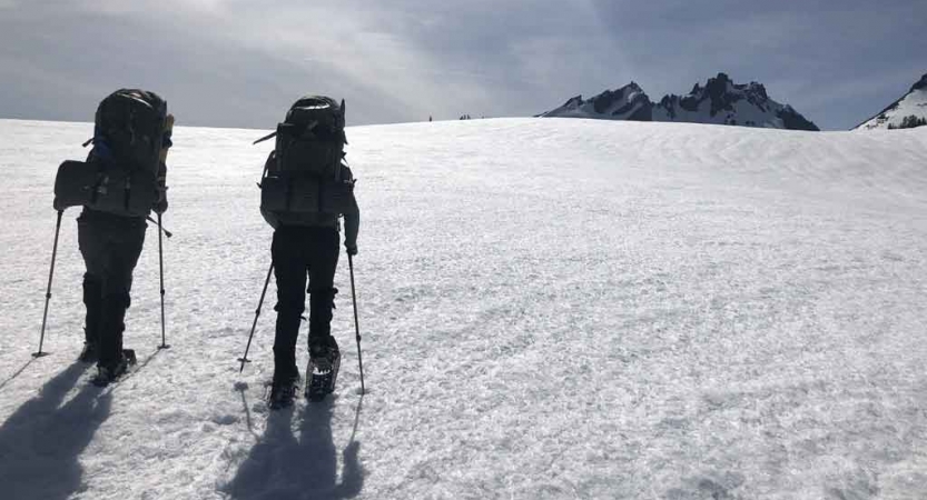 two people ascend a snowy incline on an outward bound outdoor educator course